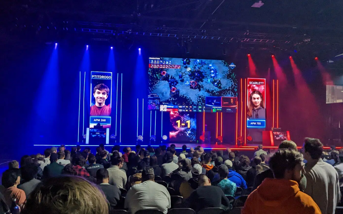 A man and woman play against each other in starcraft 2 on the dreamhack stage. The woman's APM value is 755.
