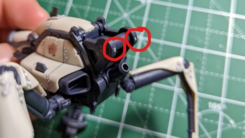 Two white blemishes are circled on a dark grey piece of a model kit