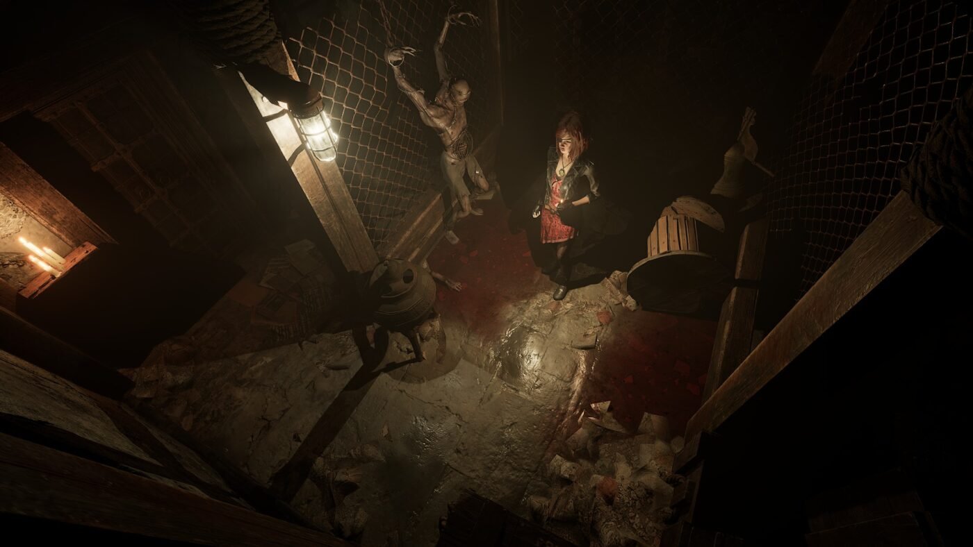 Image of a young woman standing by a corpse tied to a chain-link fence.